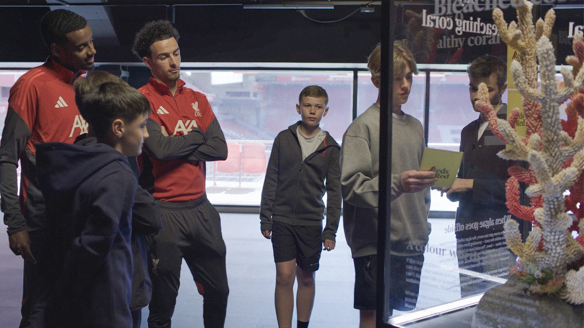 Curtis Jones and Alexander Isak with children in front of the coral sculpture at Anfield